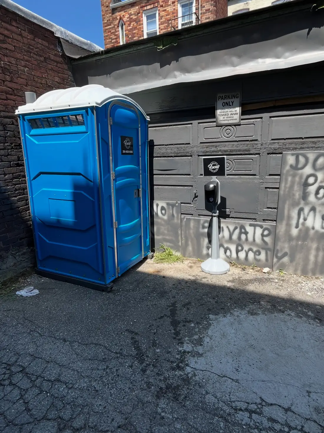 Blue porta potty and hand-wash station on a paved lot