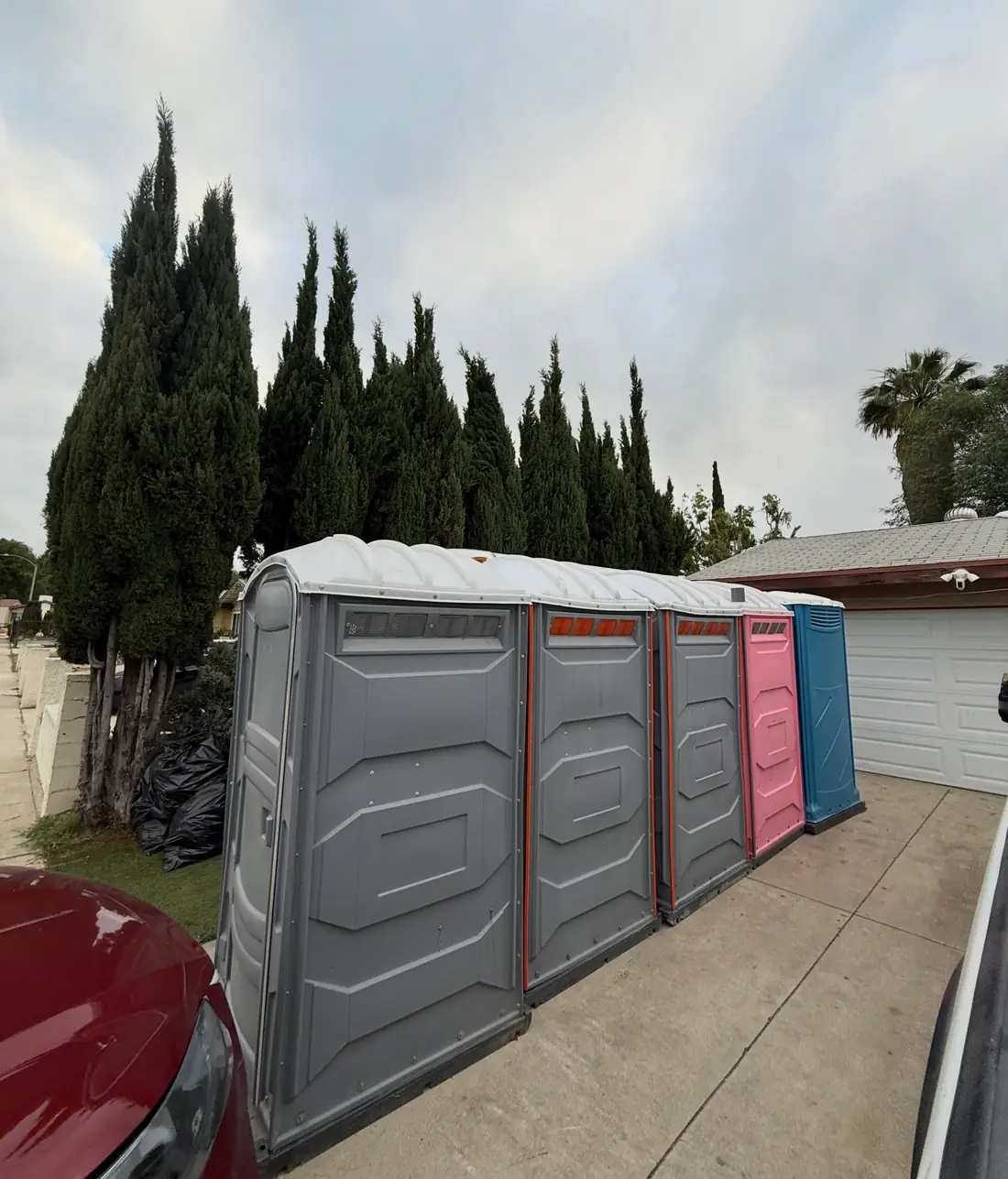 Gray, pink and blue porta potties lined up on a driveway