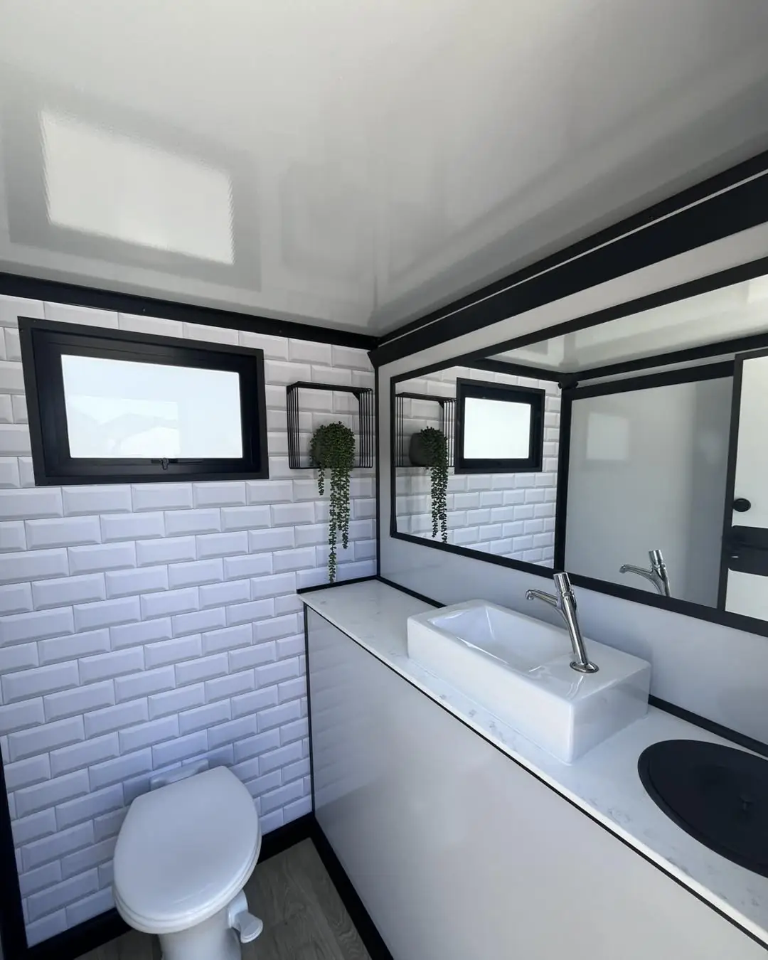 Restroom trailer interior with a white vessel sink, mirror and soap dispensers